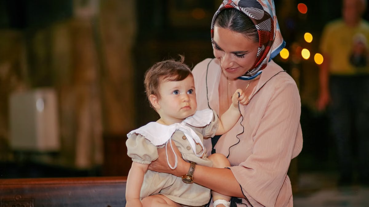 A mother lovingly holds her baby during a church ceremony.